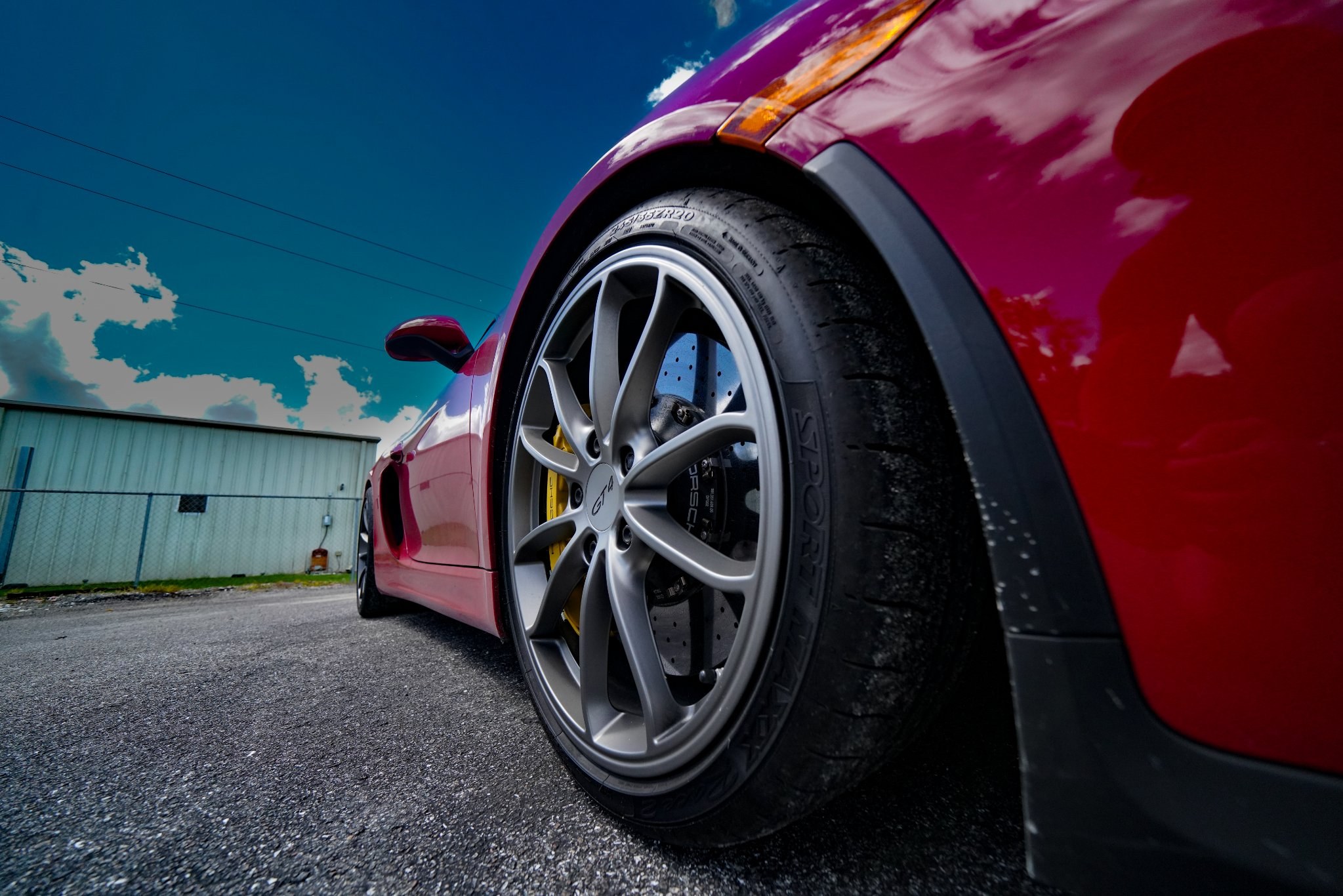 Low-angle detail photo of a red sports car wheel and brake