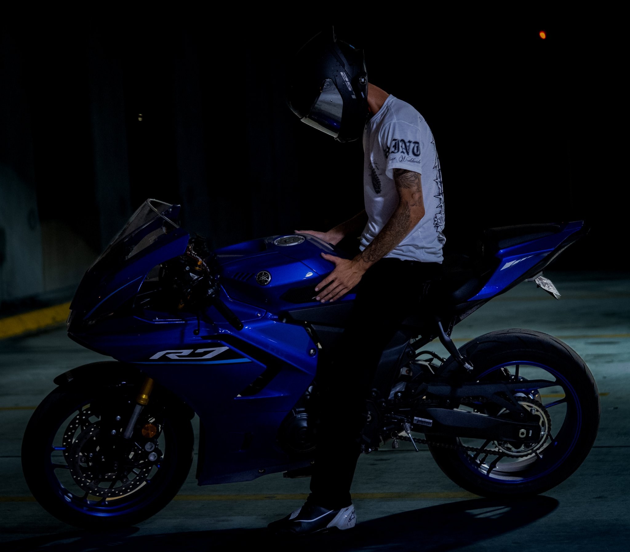 Helmeted rider seated on a blue sport motorcycle at night