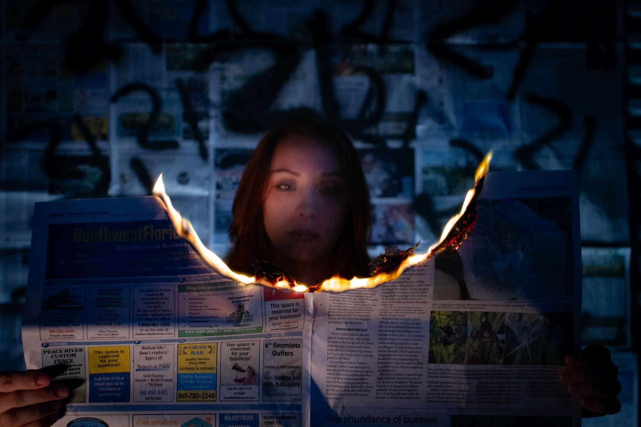 Woman holding a burning newspaper, lit by the flames