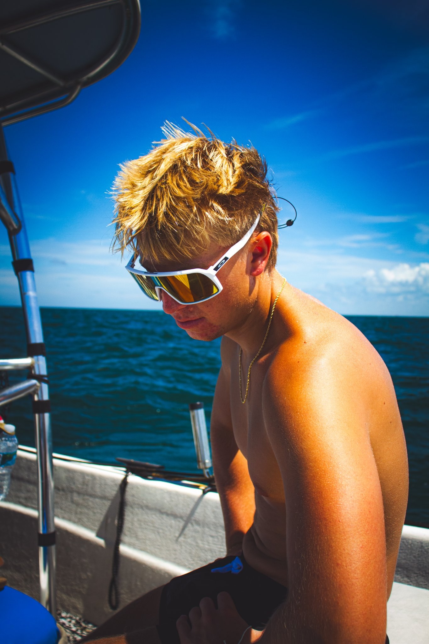 Young man in sunglasses on a boat under a bright blue sky